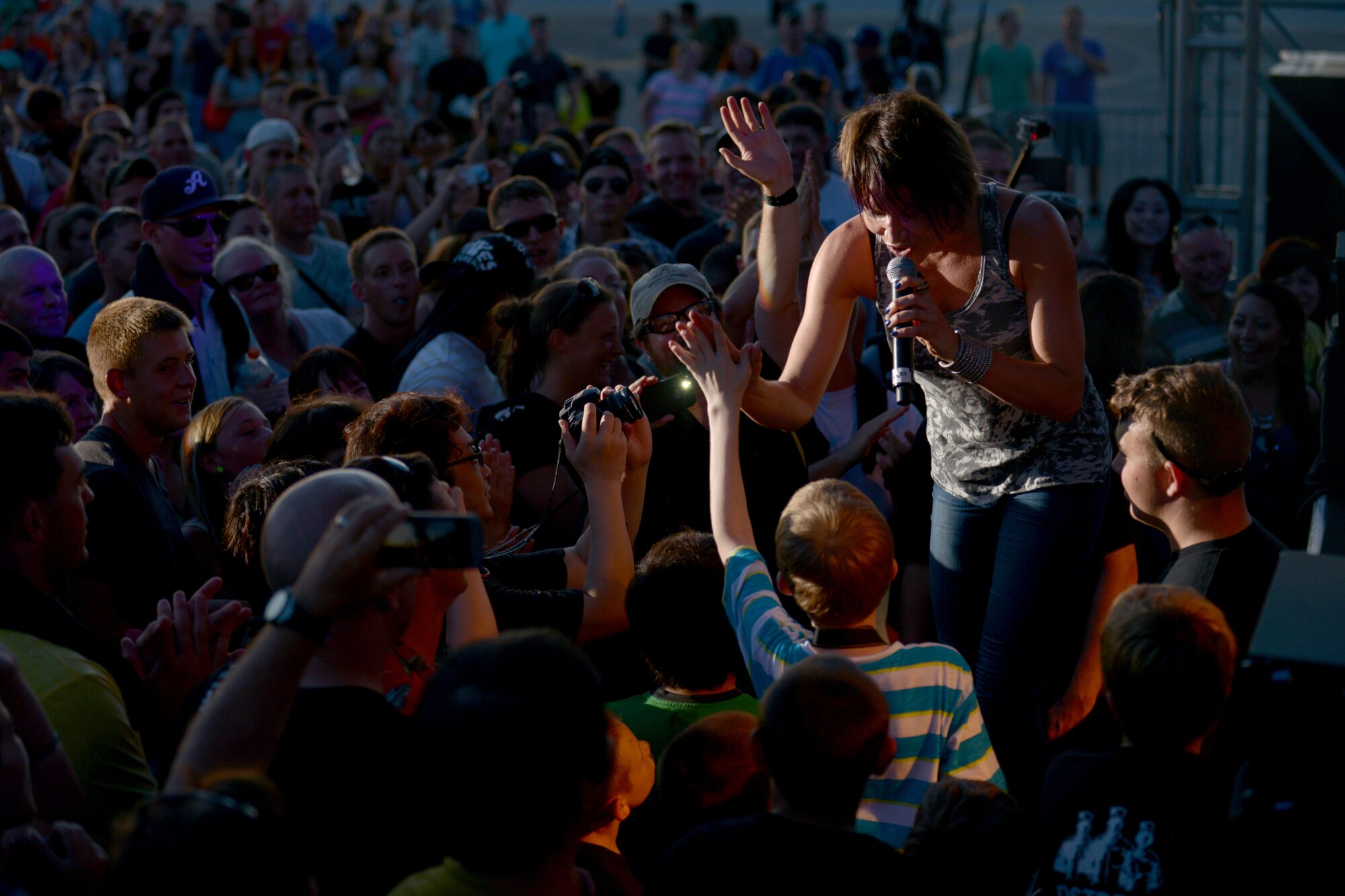 Molly Callinan, vocalist with the Lt. Dan Band, gets down with the crowd during her performance on U.S. Marine Corps Air Station Futenma, Japan, July 6, 2013. This was the Lt. Dan Band's last show on their USO tour of Pacific bases. (U.S. Air Force photo by Tech. Sgt. Jocelyn Rich-Pendracki/Released)