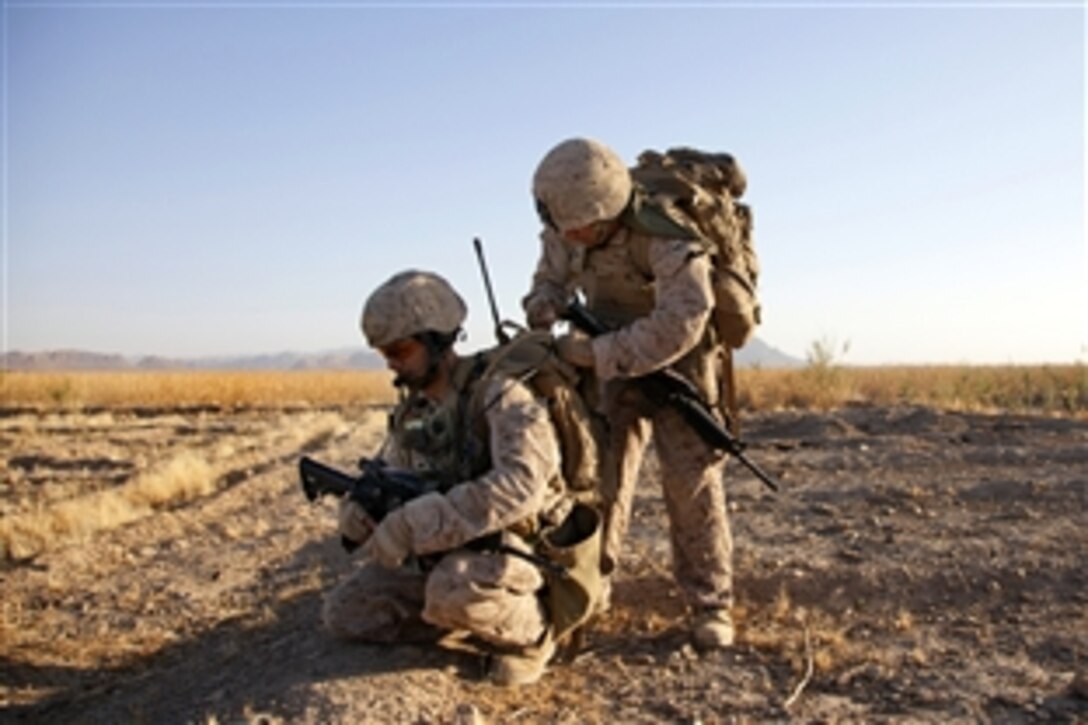 U.S. Navy Petty Officer 3rd Class Ricardo Arrequin, right, adjusts U.S. Marine Corps Cpl. Arnold H. Cabral's gear as he relays a radio message during Operation Northern Lion II in Helmand province, Afghanistan, July 3, 2013. Arrequin, a hospital corpsman, and Cabral are assigned to Georgian Liaison Team 9. The Georgian soldiers led the operation to deter insurgents, establish a presence and gather human intelligence in the area.