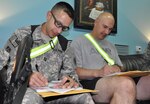 Capt. Kevin Leslie, left, and Capt. Richard Uggen, both of the Indiana Army National Guard, fill out paperwork, Aug. 12, 2009 before they read books to their children back home. With United Through Reading, deployed Soldiers with Task Force 38 are able to record themselves reading a book and send the book with the recording home to their families.