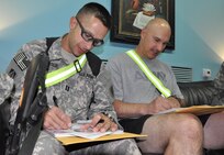 Capt. Kevin Leslie, left, and Capt. Richard Uggen, both of the Indiana Army National Guard, fill out paperwork, Aug. 12, 2009 before they read books to their children back home. With United Through Reading, deployed Soldiers with Task Force 38 are able to record themselves reading a book and send the book with the recording home to their families.