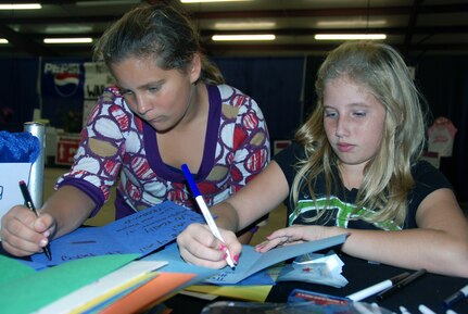 Madelyn Dassel, 11, and Bethany Pate, 11, both of Millbrook, Ala., write thank you cards for a military child from Alabama. Madelyn and Bethany took time to make the cards while visiting an Autauga County Supporting Military Families booth at this year's Autauga County Fair held in Prattville, Ala,. Their cards will be placed inside Hero Packs and given to a military child at a Yellow Ribbon program event.