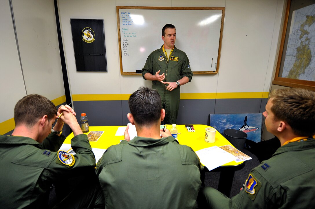U.S. Air Force pilots from the 14th Fighter Squadron conduct a mission brief before competing in a turkey shoot at Misawa Air Base, Japan, June 28, 2013. The 13 and 14 FSs competed against each other to see which squadron could more accurately engage ground targets. (U.S. Air Force photo by Staff Sgt. Nathan Lipscomb)