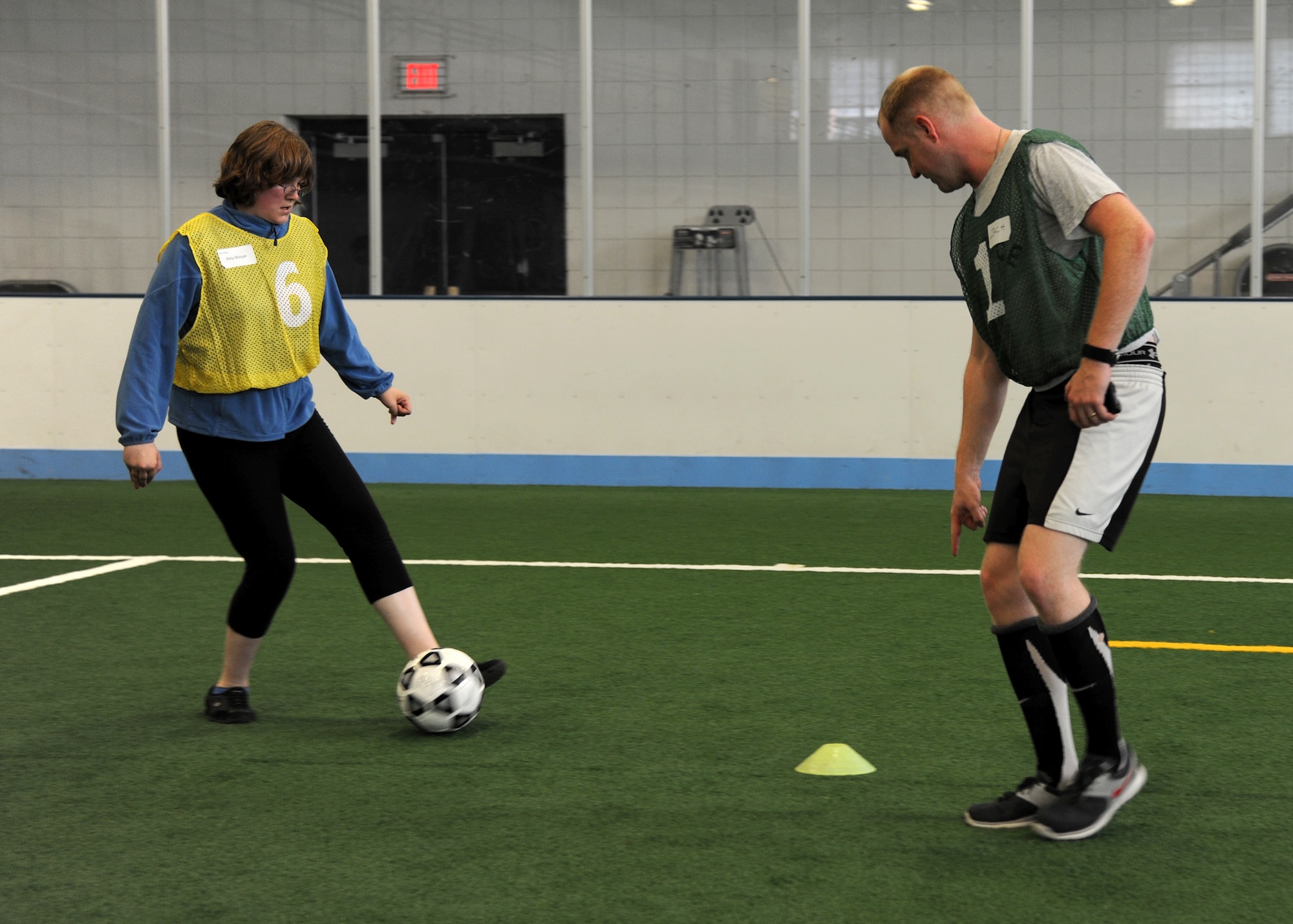 Capt. Zachary Deshetler, 69th Reconnaissance Group, teaches Special Olympic athlete Amy Winzer how to dribble a soccer ball on June 26, 2013, at the Unified Soccer Expo on Grand Forks Air Force Base, N.D. Different obstacles were arranged to teach fundamentals of soccer before putting the Special Olympians to the test by playing four five-on-five soccer matches. This was the first Special Olympics event held on base since the 1980s, and the event brought Airmen and Special Olympic athletes together to play soccer. (U.S. Air Force photo/Airman 1st Class Ashley Nicole Taylor) 
