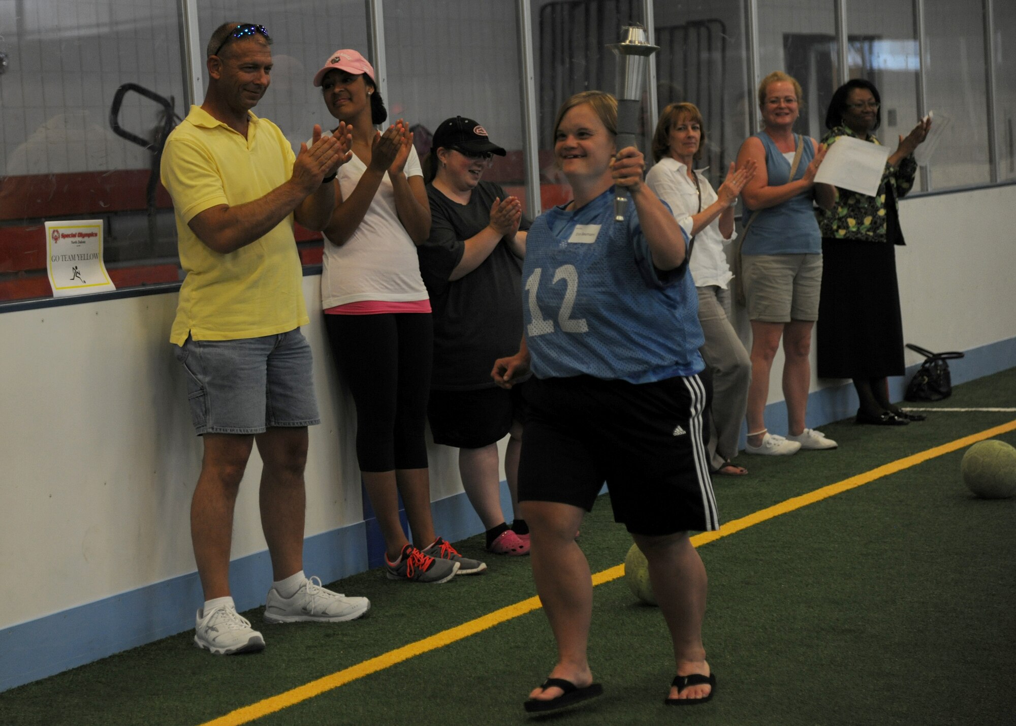 Erin Baumann, Special Olympics athlete, carries the Olympic Torch during the opening ceremony of the Unified Soccer Expo, June 26, 2013, on Grand Forks Air Force Base, N.D. At each Special Olympics North Dakota event, the games are officially opened when the Flame of Hope is lit. (U.S. Air Force photo/Airman 1st Class Ashley Nicole Taylor)
