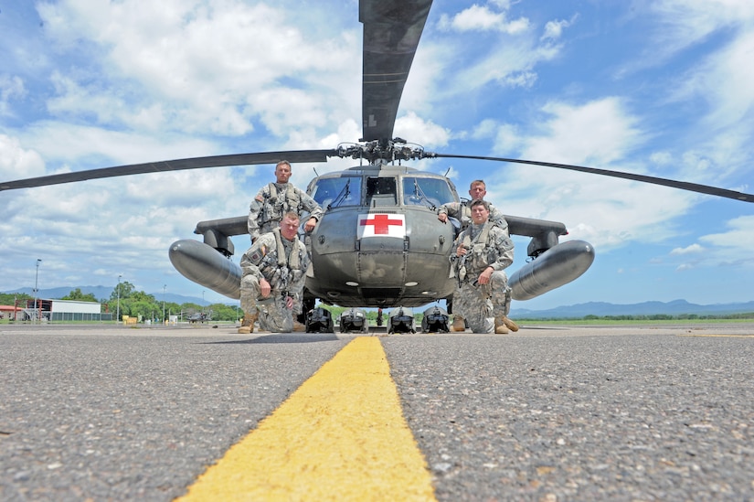 Members of Joint Task Force-Bravo’s 1-228 Aviation Battalion flight crew U.S. Army Warrant Officer-1 Zachary Lugu(top left),pilot,  U.S. Army Sgt. U.S. Army Sgt. Travis Mayo, flight medic(left front), U.S. Army SPC  Robert Clement (right front), crew chief, and U.S. Army Chief Warrant Officer-3 Jay Hanshaw pose for a photo infront of a Utility Helicopter-60 (UH-60) here July 9, 2013. The flight crew supported U.S. Southern Command’s coordinated search and rescue efforts, which located a stranded vessel and saved the lives of two Americans, one Canadian and six Hondurans, July 3.   