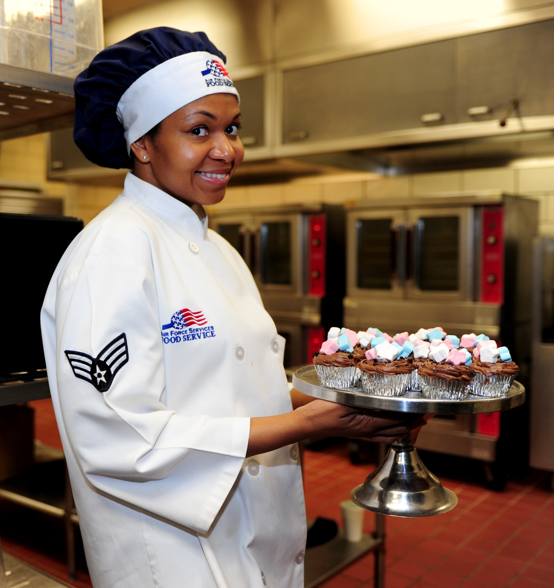U.S. Air Force Senior Airman Ashli Phillips, 633rd Force Support Squadron chef, poses for a photo before taking her team’s cupcakes out to be judged during the 633rd FSS Cupcake Challenge at the Langley Air Force Base Va. Crossbow Dining Facility, July 3, 2013. The 633rd FSS hosts the event to showcase the talent of the squadron’s members. (U.S. Air Force photo by Airman Areca T. Wilson/Released)