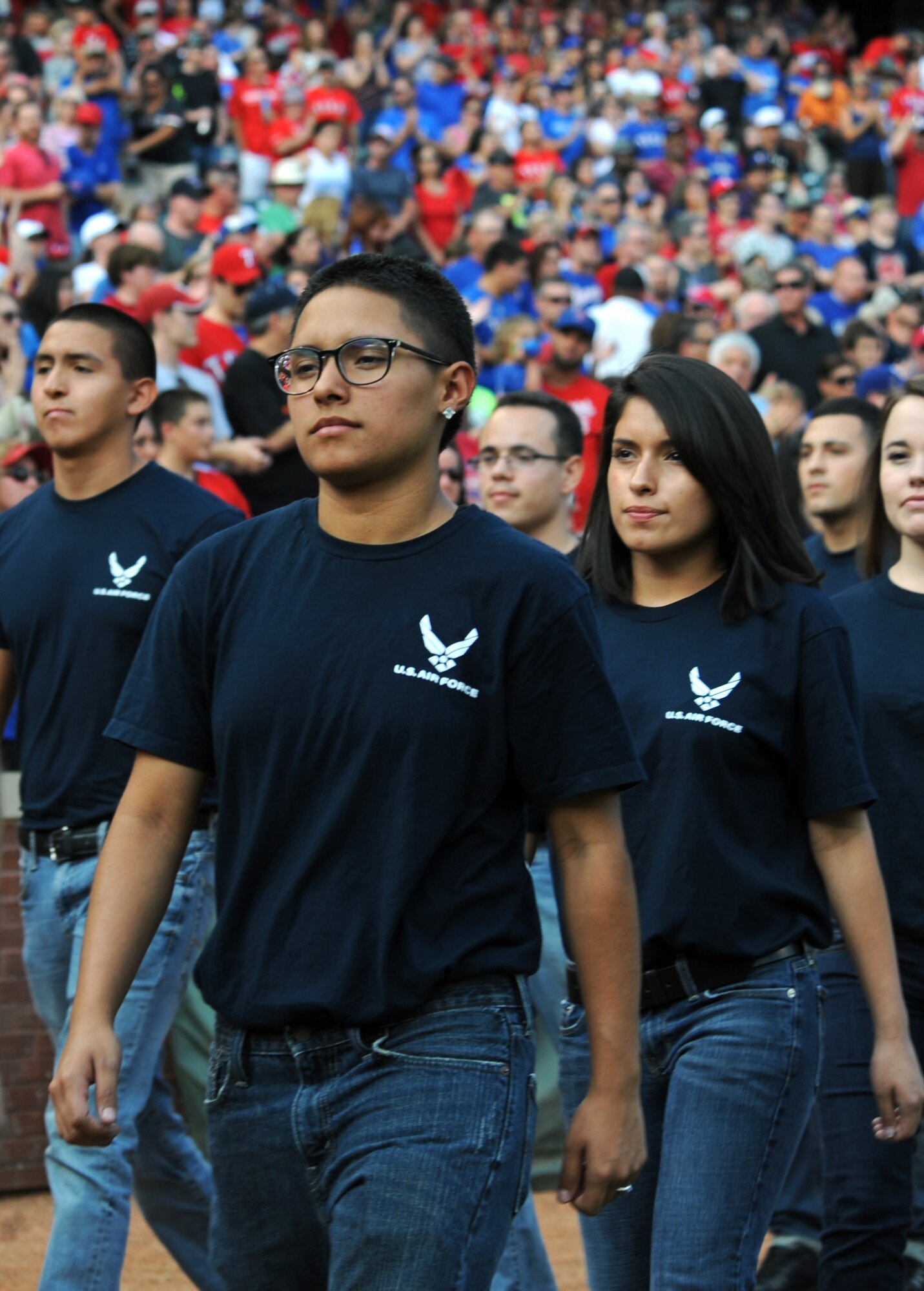 Elizabeth Martinez, left, and Katherine Martinez, daughters of Dyess Air Force Base Tech. Sgt. Craig Cooper, walk onto the field July 4, 2013, at Rangers Ballpark in Arlington, Texas. Elizabeth enlisted on the Rangers baseball team’s field prior to the start of a game, along with more than 150 other Air Force recruits, while Katherine, a Navy recruit, wore an Air Force shirt in support of her sister. (U.S. Air Force photo by Airman 1st Class Peter Thompson/Released)