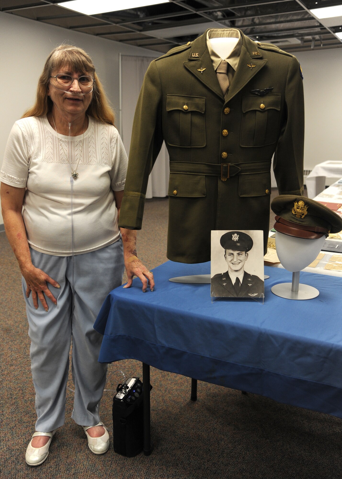 PETERSON AIR FORCE BASE, Colo. – Vicki Lea Huskey, daughter of Peterson AFB’s namesake, Lt. Edward Peterson, stands next to a photo of her father wearing the displayed uniform during her first-ever visit to the base, July 2. Vicki never knew her father as she was born after his death. Vicki and her family, from Wichita, Kan., spent the day touring the museum and myriad static displays learning everything they could about Lt. Peterson. They ended the day pouring over a table laden with Peterson’s personal effects. (U.S. Air Force photo/Staff Sgt. J. Aaron Breeden)