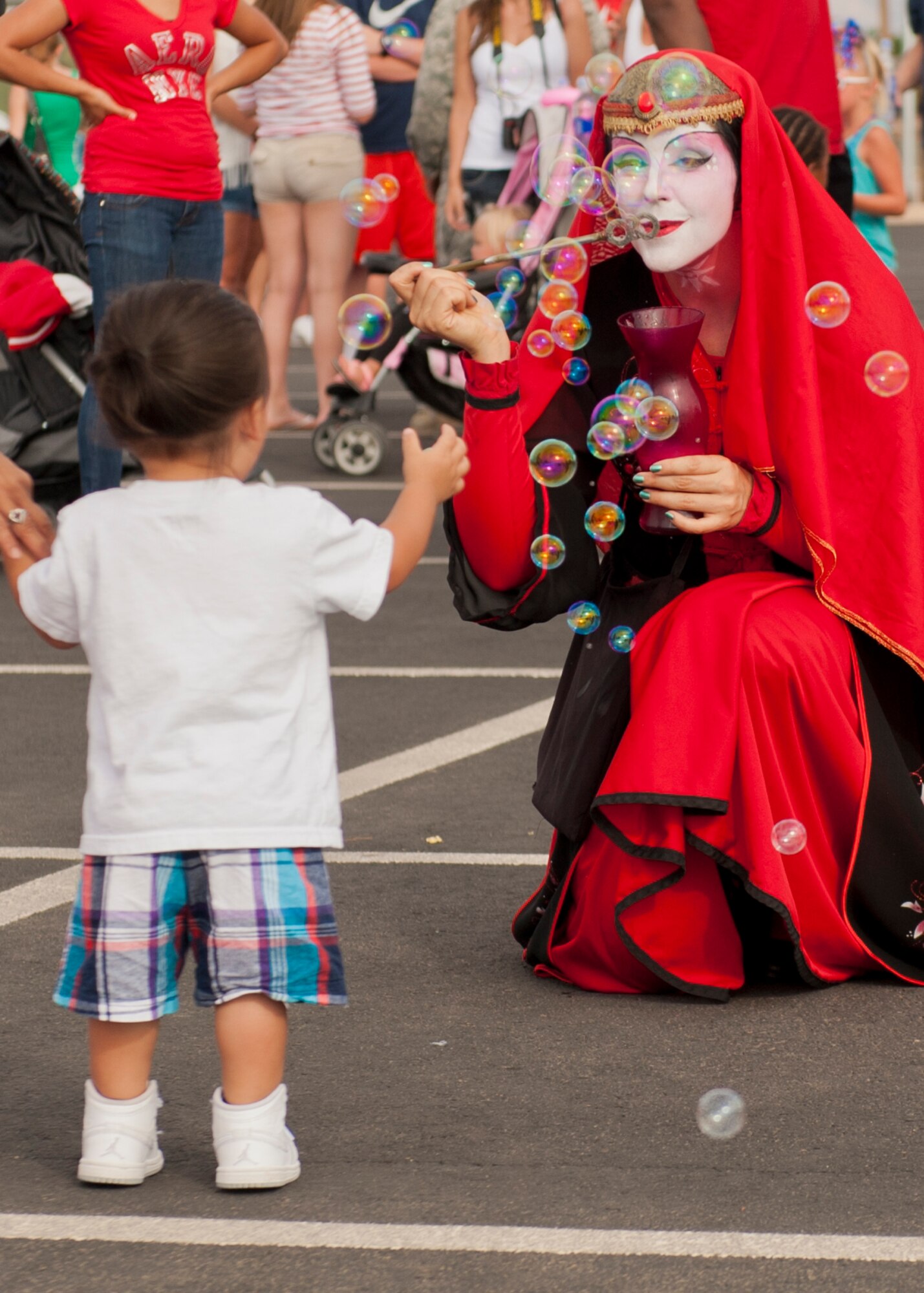 A child catches bubbles with a member of the Clan Tynker performance group at the Freedom Fest Independence Day celebration at Holloman Air Force Base, N.M., July 3. Freedom Fest took place in the Domenici Fitness and Sports Center parking lot and included carnival games, rides, and live music for Airmen and their families. (U.S. Air Force photo by Airman 1st Class Aaron Montoya/Released)