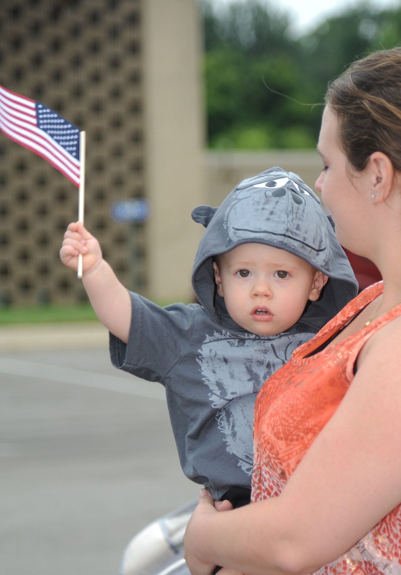 A Keesler child waves a U.S. flag while his mother holds him at a circus event July 3, 2013, at the Mississippi Coast Coliseum.  Members of Keesler deployed families were invited to participate in a walking parade with the elephants followed by a picnic.  (U.S. Air Force photo by Kemberly Groue)