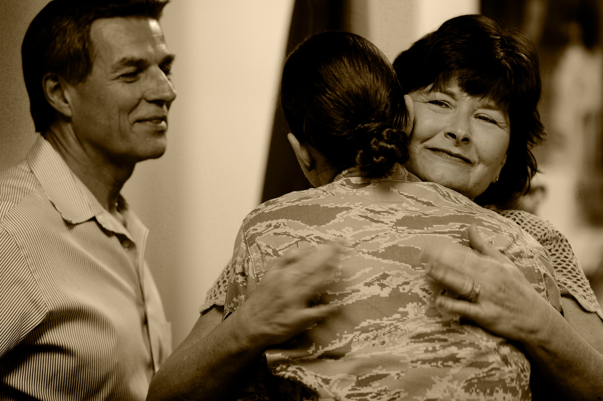 U.S. Air Force Staff Sgt. Alisha Martell, Air Forces Central intelligence analyst, hugs her mother as her father stands by upon the conclusion of her retirement ceremony, March 29, 2013, Shaw Air Force Base, S.C. Martell retired from active duty due to thyroid cancer which she battled throughout her Air Force career. (U.S. Air Force photo by Staff Sgt. Kenny Holston/Released)