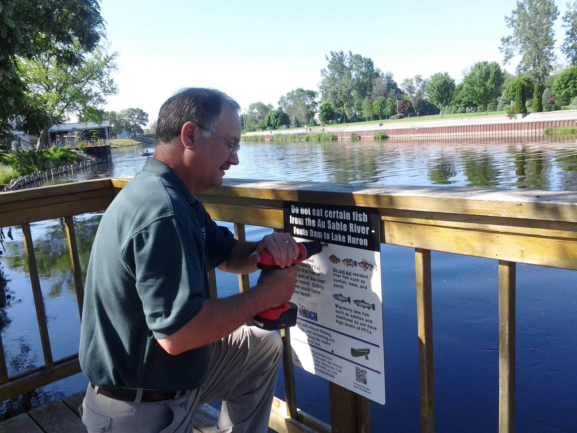 FORMER WURTSMITH AIR FORCE BASE, Mich. -- Dave Strainge, Air Force Civil Engineer Center environmental coordinator for the former Wurtsmith Air Force Base, puts up a fishing advisory sign June 26, 2013, on the AuSable River. The signage is one of the ways AFCEC is working with state health and environmental agencies to inform residents of the presence of perflourinated compounds, an emerging contaminant found in fish samples taken from the river in 2012. The center works closely with the Environmental Protection Agency and the Michigan Department of Environmental Quality to ensure environmental cleanup activities satisfy all regulatory standards while protecting human health and the environment. Strainge is a member of the AFCEC Installations Directorate base realignment and closure program management division. (Courtesy photo)