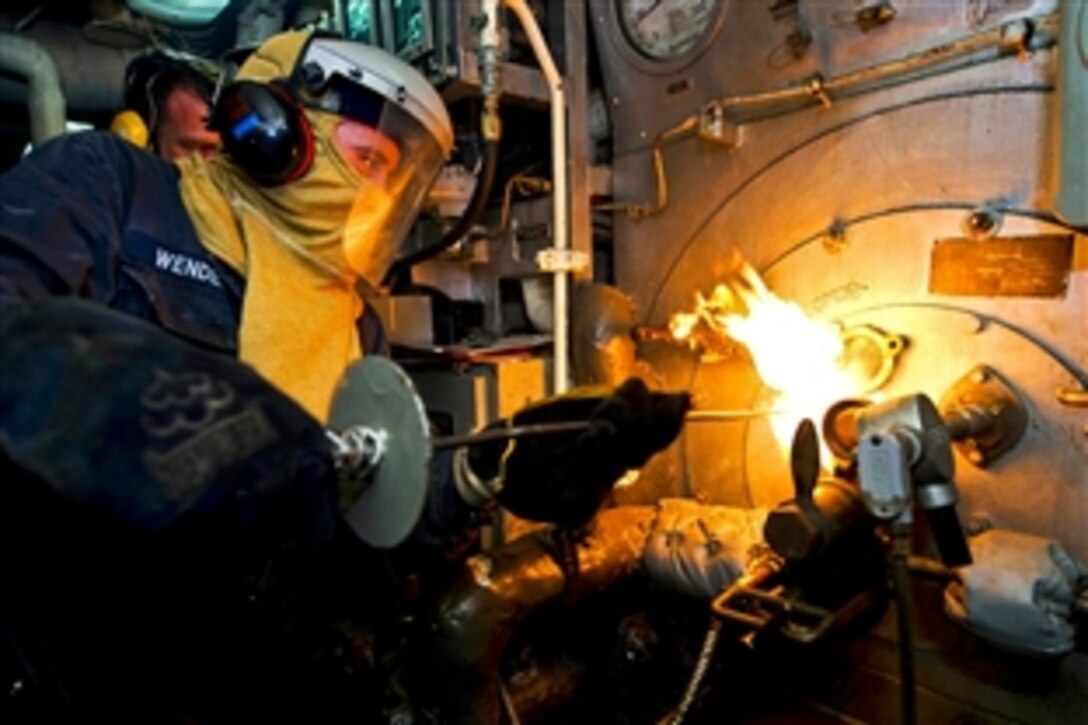 U.S. Navy Petty Officer 3rd Class Alexander Wendell inserts a torch into a boiler during a manual boiler check aboard the amphibious dock landing ship USS Carter Hall in the Persian Gulf, July 8, 2013. The Hall, part of the Kearsarge Amphibious Ready Group, is supporting maritime security operations and theater security cooperation efforts in the U.S. 5th Fleet area of responsibility. 