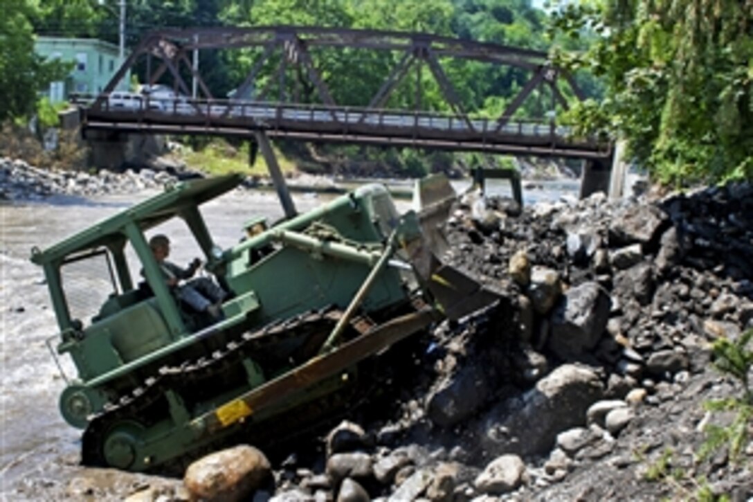 Army Pfc. Michael Bykowicz uses a bulldozer to remove rocks and other flood debris from Otsquago Creek in Fort Plain, N.Y., July 4, 2013. Bykowicz is assigned to the New York National Guard's 152nd Engineer Company. The debris had choked the creek's flow.