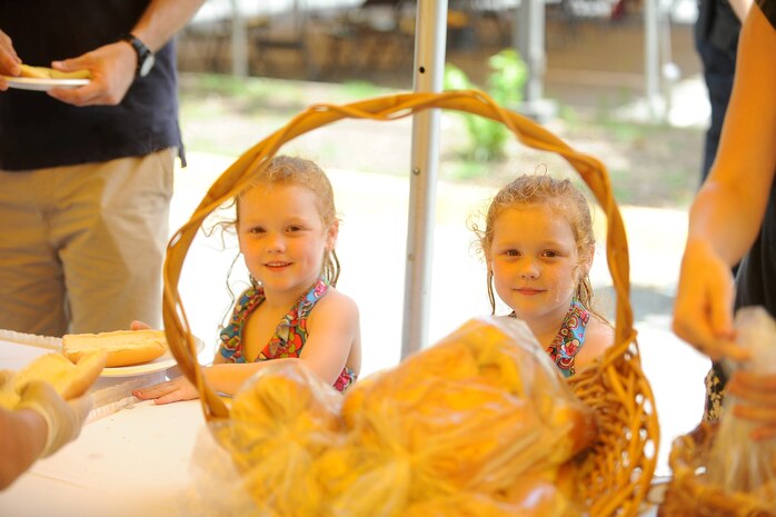 Issabella and Mikala, 4, wait in line, with their mother and father after a long swim, to get some food at the Clubs of Quantico Parking lot aboard Marine Corps Base Quantico on July 4, 2013. Included in the festivities were free pool access, music, food and children’s rides at the Quantico 50-Meter pool.