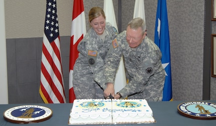 Army Capt. Christina Taylor, North American Aerospace Defense Command and U.S. Northern Command J7, and Army Lt. Gen. Frank Grass, USNORTHCOM deputy commander, cleave through the National Guard birthday cake at the NORAD and USNORTHCOM National Guard Birthday Celebration Dec. 13. Taylor received her commission in the Idaho National Guard in 2002, and Grass enlisted in the Missouri National Guard in 1969. Nearly 6,000 Guardsmen are currently on state orders performing homeland defense missions across the U.S.  

