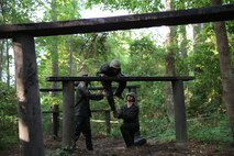 Two Marines with Food Service Company, Combat Logistics Regiment 27, 2nd Marine Logistics Group help a teammate over obstacles on the endurance course aboard Camp Lejeune, N.C., July 10, 2013.  The course took approximately two hours to complete, and ended with a swim in a pool to clean mud and debris off of service members. (U.S. Marine Corps photo by Lance Cpl. Shawn Valosin)