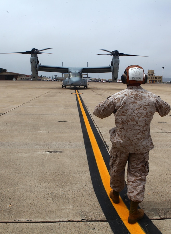 Cpl. Mark Haycroft, an MV-22B Osprey mechanic with Marine Medium Tiltrotor Squadron 363 Red Lions, 3rd Marine Aircraft Wing, and a Highland, Ark., native, guides an aircraft to its parking spot aboard Naval Air Station North Island, Calif., July 9. This aircraft is just one of 12 to be shipped to Okinawa, Japan for a new squadron.