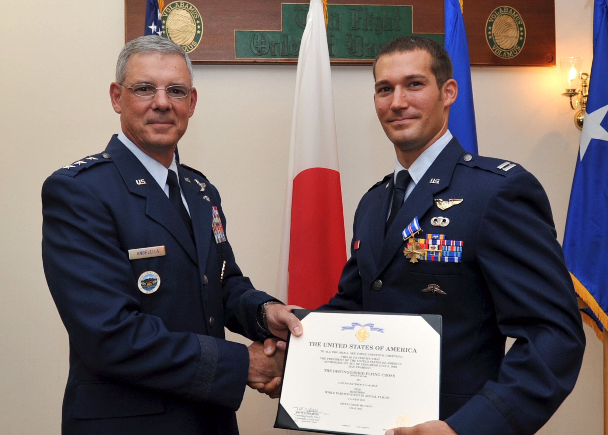 U.S. Air Force Lt. Gen. Salvatore Angelella, U.S. Forces Japan and 5th Air Force commander, awards U.S. Air Force Capt. Matthew Carlisle, 31st Rescue Squadron operations flight commander, the Distinguished Flying Cross with valor at the Officer’s Club on Kadena Air Base, Japan, July 10, 2013. Carlisle was awarded for his heroic actions during a seven-hour, 320-mile rescue mission under direct enemy gunfire in Afghanistan, Aug. 4, 2012. During the mission, Carlisle aided three critically wounded coalition soldiers. (U.S. Air Force photo by Naoto Anazawa/Released)