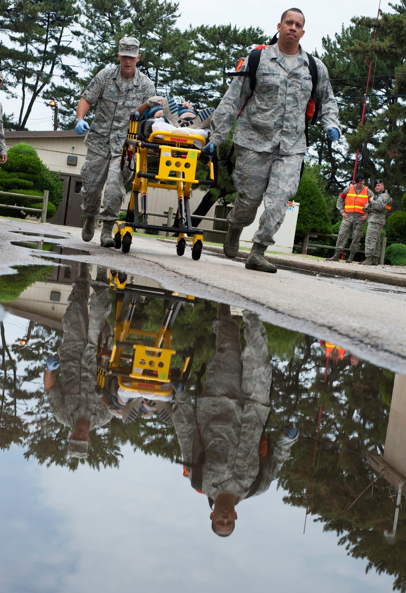 Master Sgt. Daniel White, 8th Medical Group family health superintendent, left, and Staff Sgt. Branden Coneita, 8th Medical Operations Squadron first responder, transport a patient to an ambulance at Kunsan Air Base, Republic of Korea, July 9, 2013. White and Coneita responded to an exercise scenario intended to maintain and develop skills. (U.S. Air Force photo by Senior Airman Armando A. Schwier-Morales)