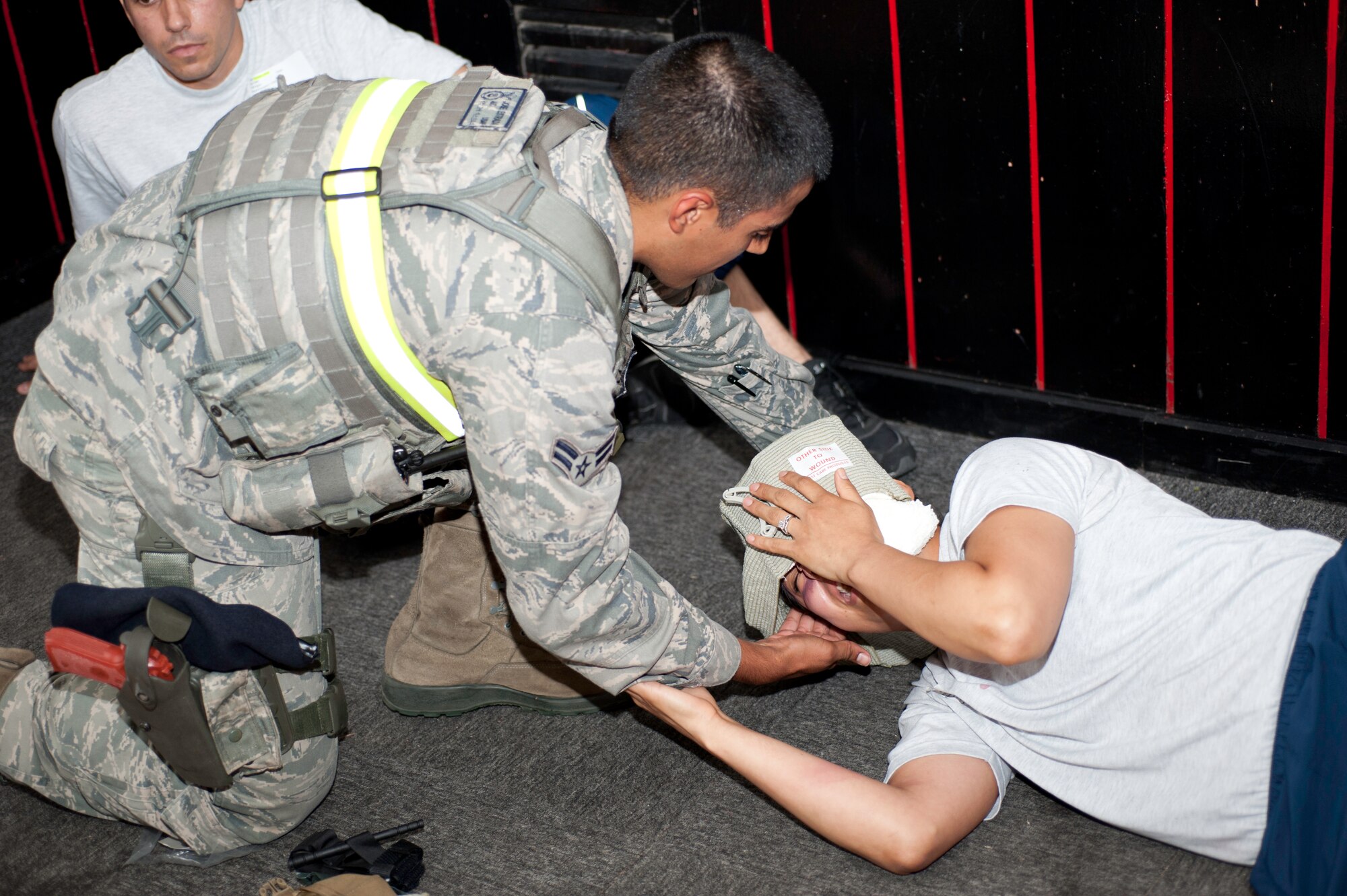 Airman 1st Class Jose Estrada, 8th Security Forces Squadron member, provides first aid to Senior Airman Rosario Warren, 8th Medical Group dental journeyman and “victim,” at Kunsan Air Base, Republic of Korea, July 9, 2013. The Wolf Pack participated in an exercise testing the bases ability to respond to an active shooter scenario.  (U.S. Air Force photo by Senior Airman Armando A. Schwier-Morales) 