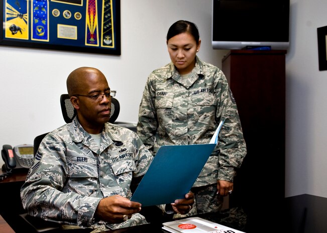 Chief Master Sgt. Robert Ellis, United States Air Force Warfare Center command chief, discusses the chief’s correspondence with Tech. Sgt. Carrie Cain, USAFWC executive assistant to the command chief, July 9, 2013, at Nellis Air Force Base, Nev. Ellis serves as the primary advisor to the commander on matters concerning the mission effectiveness, readiness, training, health, welfare and morale of more than 10,000 Airmen assigned to the four wings and one named organization under the Warfare Center.  (U.S. Air Force Photo by Airman 1st Class Jason Couillard)