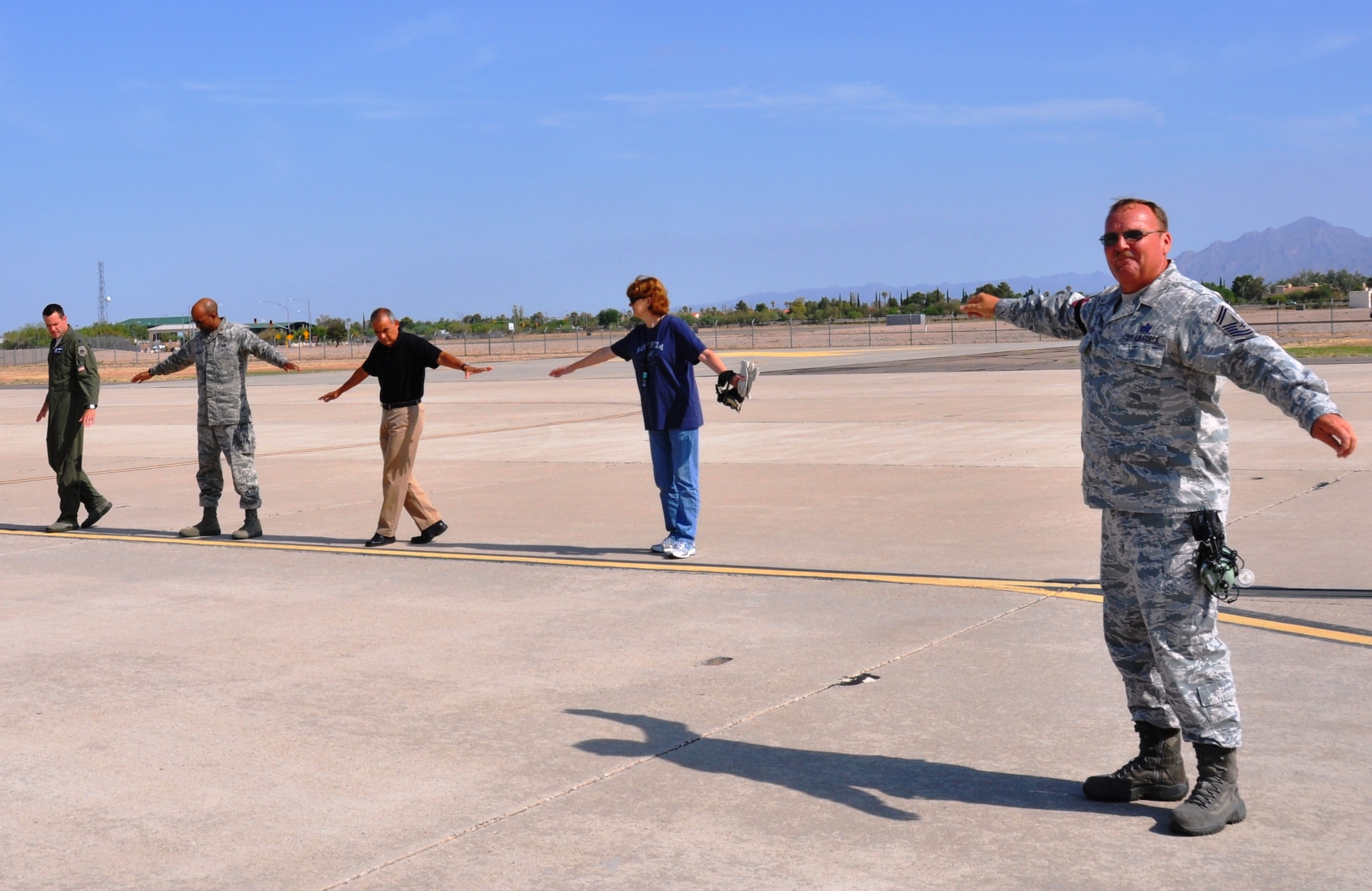 Members of the 943rd Rescue Group are lined up and spaced apart for a FOD walk on the 943rd RQG HH-60G Pave Hawk helicopter parking ramp by Senior Master Sgt. David Heffernan, 943rd Maintenance Squadron quality assurance superintendant on the morning of July 10. More than 40 members volunteered to pick up Foreign Object Debris before it causes serious aircraft damages and affects the group's resuce mission. (U.S. Air Force photo/Tech Sgt. Carlos J. Trevino)