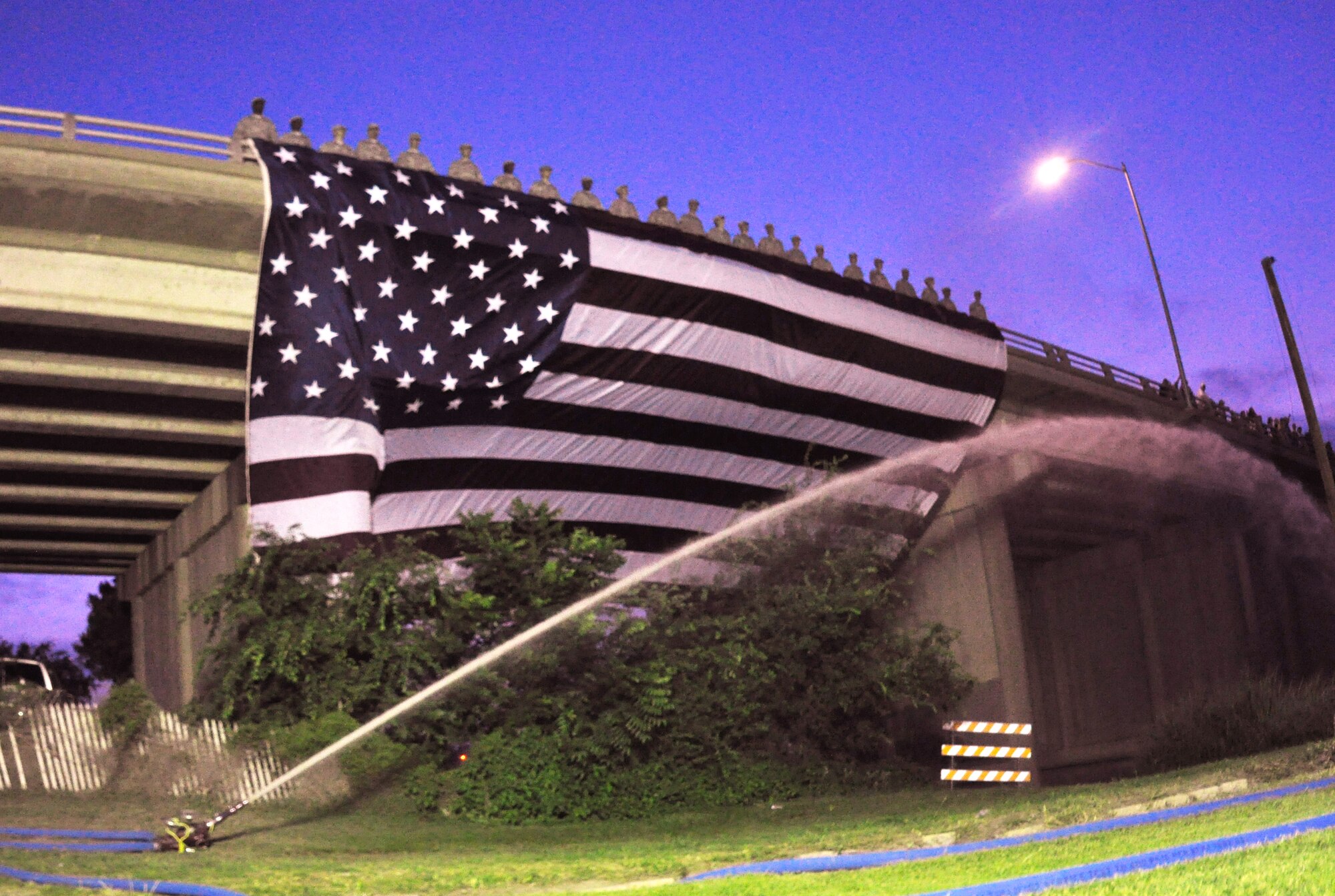 SAN ANGELO, Texas – Twenty-three soldiers from the Army 344th Military Intelligence Battalion unfurl the American flag from an overpass  for the annual July 3rd Pops Concert at the Bill Aylor Sr. Memorial River Stage . The Pops Concert featured performances from San Angelo Community Band and San Angelo Symphony as well as a firework show. (U.S. Air Force photo/ Airman 1st Class Joshua Edwards)