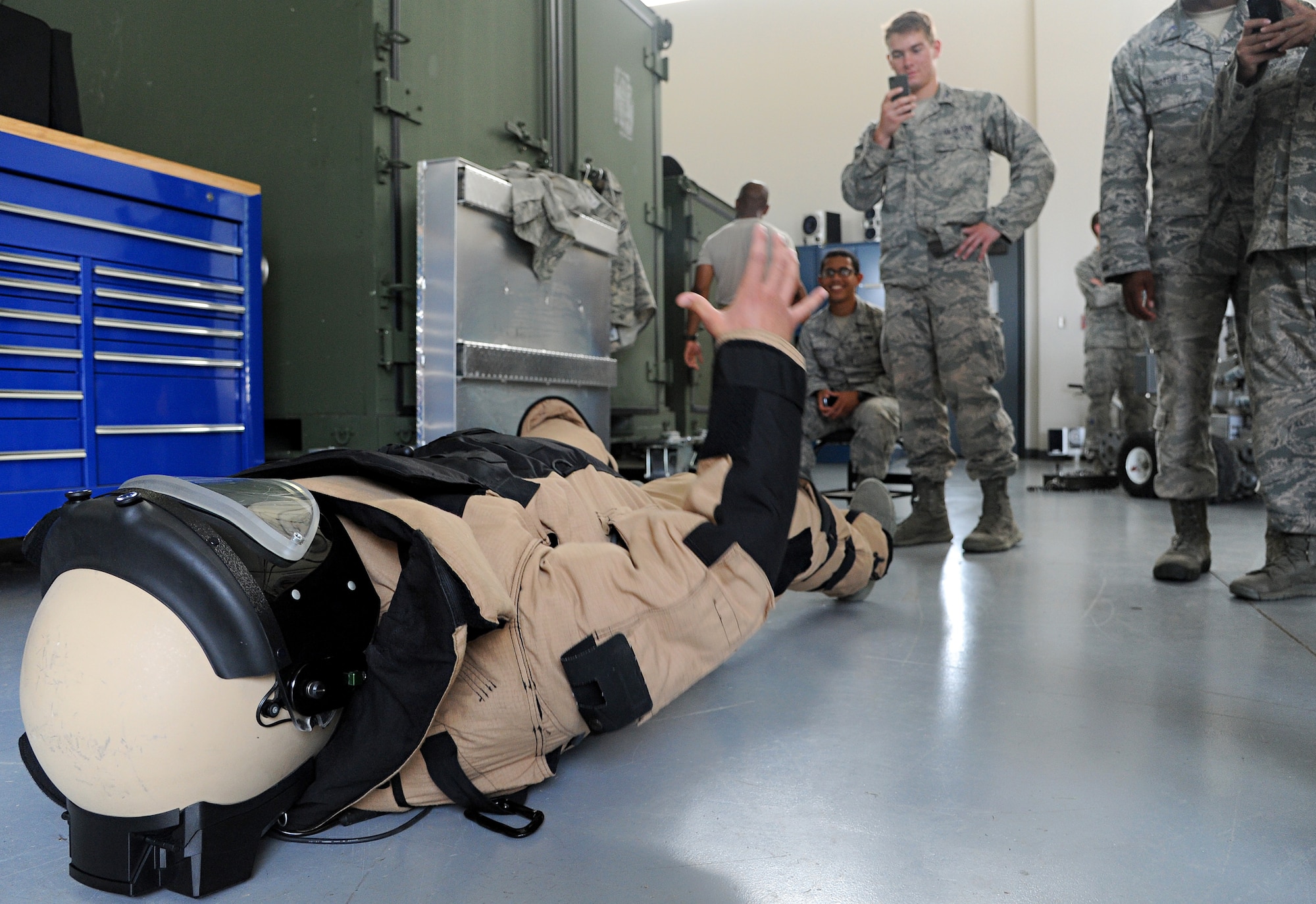 A cadet from the United States Air Force Academy tries to lift himself off of the ground after donning an 80-pound bomb suit used by Explosive Ordnance Disposal July 8 at Scott Air Force Base, Ill. The cadets visited several flights within the 375th Civil Engineer Squadron for a day and got to learn about the different jobs and experiences that each flight experiences. (U.S. Air Force photo/Airman 1st Class Kristina Forst)