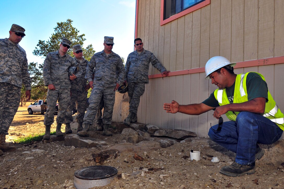 Larson Manuelito Jr. right, a plumber, talks to soldiers and airmen about the site prep for a future home through Innovative Readiness Training's Footprint project in Gallup N.M., July 9, 2013.