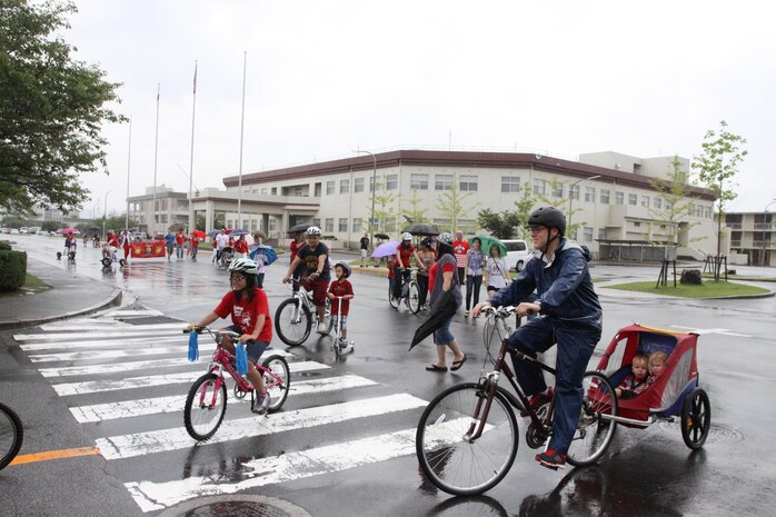 Participants ride bikes, scooters and walk during the Headquarters and Headquarters Squadron Independence Day Parade that circled the Parade deck block aboard station, July 4, 2013.