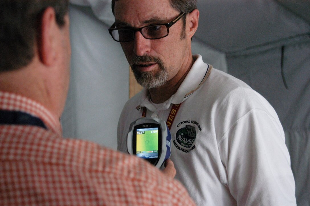 Naval Surface Warfare Center Panama City Division (NSWC PCD) engineers Bob Backus (left) and Ray Sheffield (right) use a hand held thermal imaging device April 26, 2013 to determine heat levels inside a tent being used for energy absorbtion and monitoring research conducted at NSWC PCD.