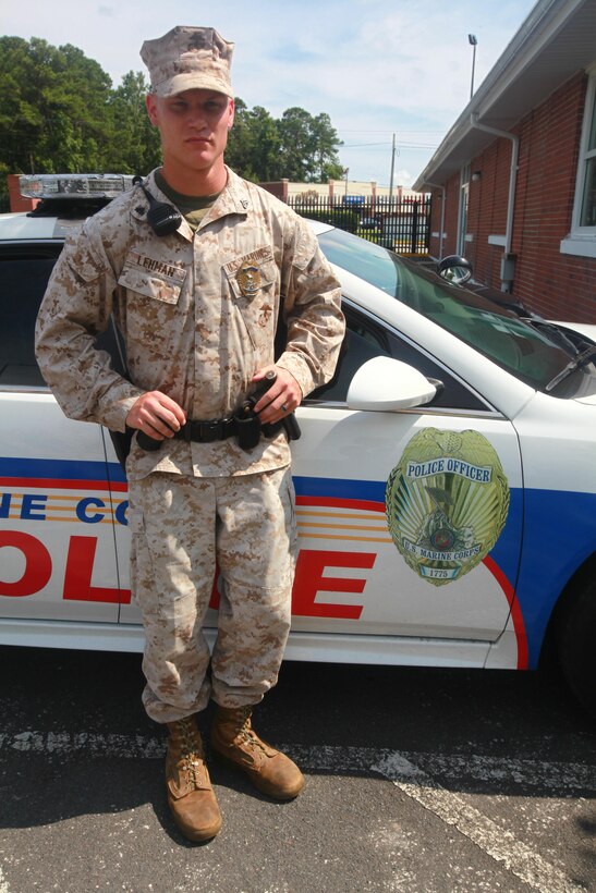 Cpl. Anthony M. Lehman, a military poilice officer with Headquarters and Headquarters Squadron, stands next to a patrol car just inside the main gate July 9. When Lehman was young, his dream was to become a police officer.