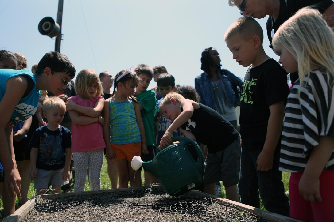 Exceptional Family Member Program children help water potato seeds as part of a science class at the Scarlet and Gold Riding Club aboard Marine Corps Base Camp Lejeune, May 15. The children planted potato seeds during the class.