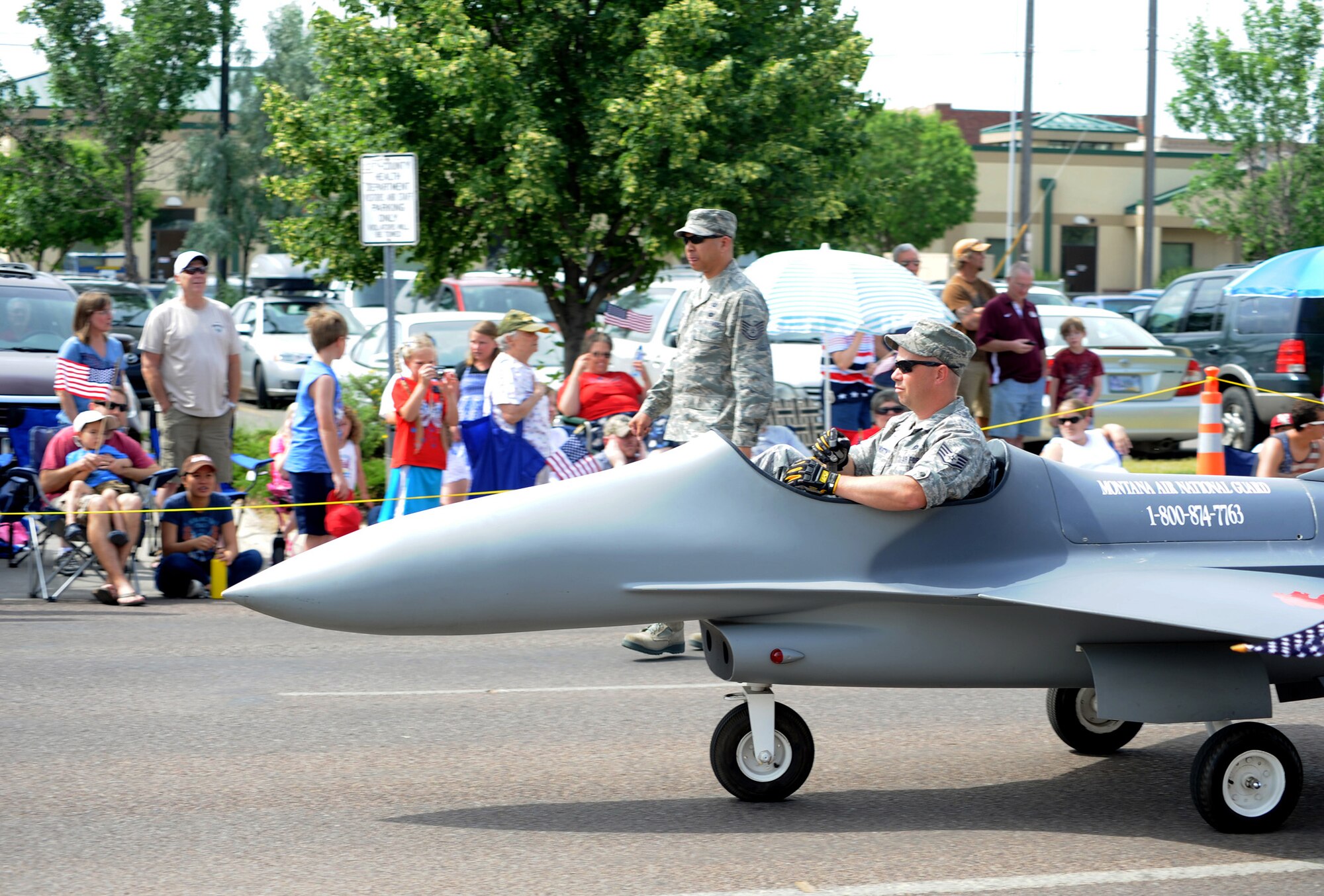 Tech. Sgt. Joel Enriquez (left) and Staff Sgt. Ralph Hayworth, members of the 120th Fighter Wing of the Montana Air National Guard, operate a miniature F-16 Fighting Falcon during the Great Falls, Mont., Independence Day Parade. Malmstrom Air Force Base Honor Guard members and Col. Robert Stanley, 341st Missile Wing commander, were also featured in the parade. (U.S. Air Force photo/Staff Sgt. R.J. Biermann)