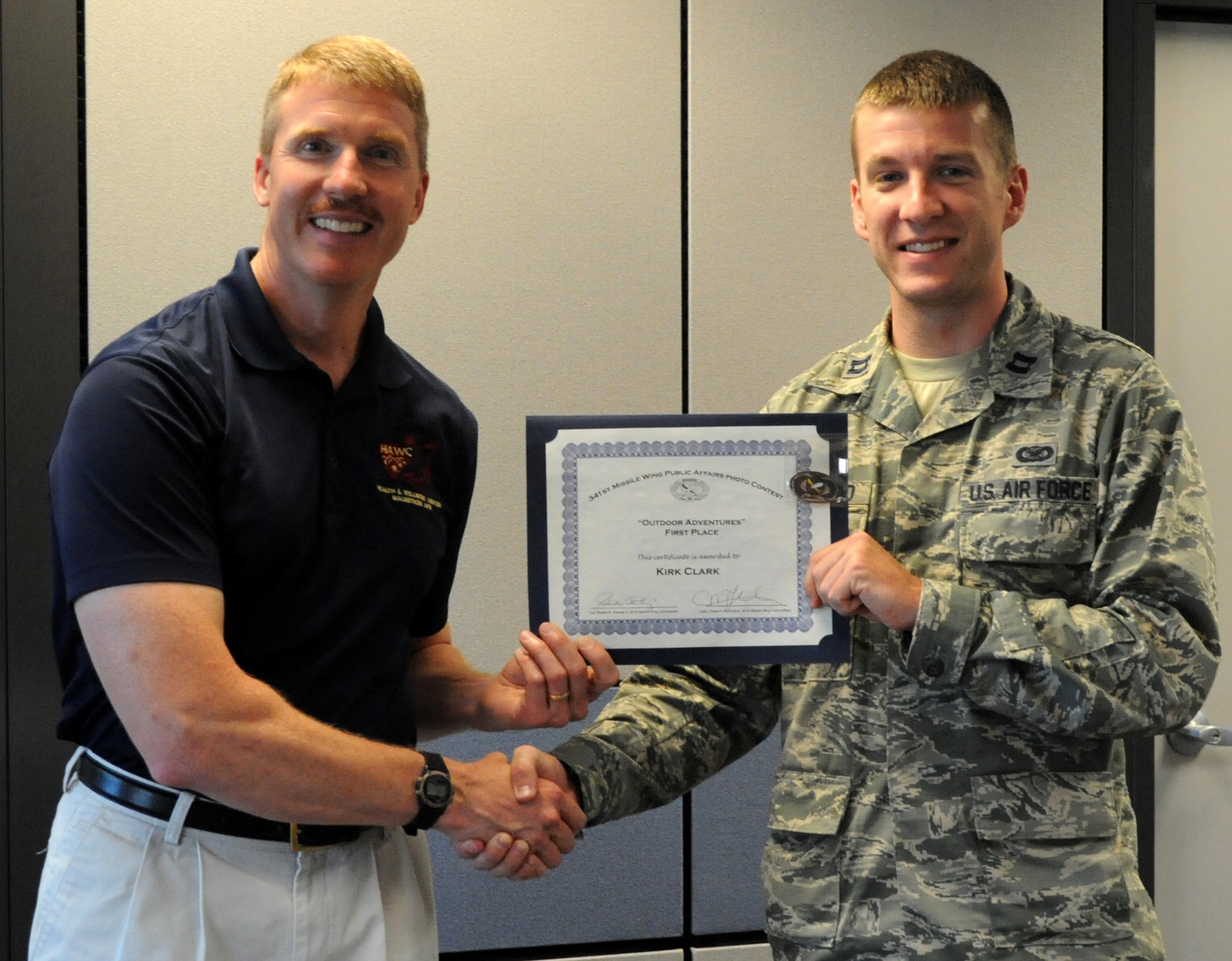 Capt. Chase McFarland, 341st Missile Wing Public Affairs office deputy chief, presents a certificate and coin to Kirk Clark, Health and Wellness Center exercise physiologist, for his first place entry in Malmstrom’s Quarterly Amateur Photo Contest on July 9 at the HAWC. Clark’s photograph captured the essence of outdoor adventures, the theme for this quarter’s competition. (U.S. Air Force photo/Airman 1st Class Collin Schmidt) 