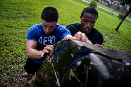 Airman 1st Class Lazaro Lazabal, 628th Comptroller Squadron customer service technician, and Staff Sgt. Gregory Hamlin, 628th Comptroller Squadron travel supervisor, roll a tractor tire up a hill during a physical training session July 10, 2013, at Joint Base Charleston – Air Base, S.C.  More than 20 Airmen from the 628th CPTS split into groups and accomplished three workout stations before finishing the PT session with aquatic exercises at the JB Charleston – AB pool. (U.S. Air Force photo / Senior Airman Jared Trimarchi)