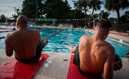 Senior Master Sgt. Benjamin Manalastas, 628th Comptroller Squadron superintendent,  and Airman 1st Class Dustin Davis, 628th Comptroller Squadron customer service technician, do a set of exercises with medicine balls after swimming laps in the pool at Joint Base Charleston – Air Base, S.C.  More than 20 Airmen from the 628th Comptroller Squadron split into groups and accomplished three workout stations before finishing the PT session with aquatic exercises in the JB Charleston – Air Base Pool. (U.S. Air Force photo / Airman 1st Class Tom Brading)