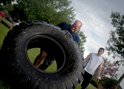 Senior Master Sgt. Benjamin Manalastas, 628th Comptroller Squadron superintendent, flips a tractor tire during the tire-tossing portion of the pool PT exercise July 10, 2013, at JB Charleston – Air Base, S.C. More than 20 Airmen from the 628th Comptroller Squadron split into groups and accomplished three workout stations before finishing the PT session with aquatic exercises in the JB Charleston – Air Base pool. (U.S. Air Force photo / Airman 1st Class Tom Brading)