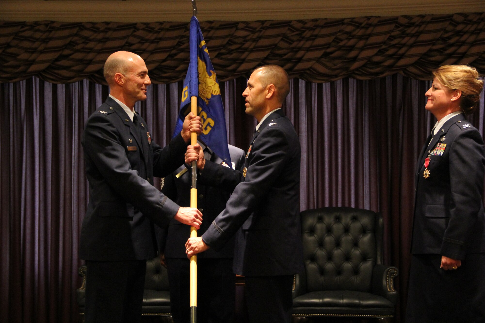 Col. Christopher Azzano, left, 72nd Air Base Wing and Tinker installation commander, transfers the 72nd Mission Support Group guidon to the new group commander, Col. Todd Vician, while the immediate past commander, Col. Julie Boit, watches. (Air Force photo by Tech. Sgt. Tamica DuBose)