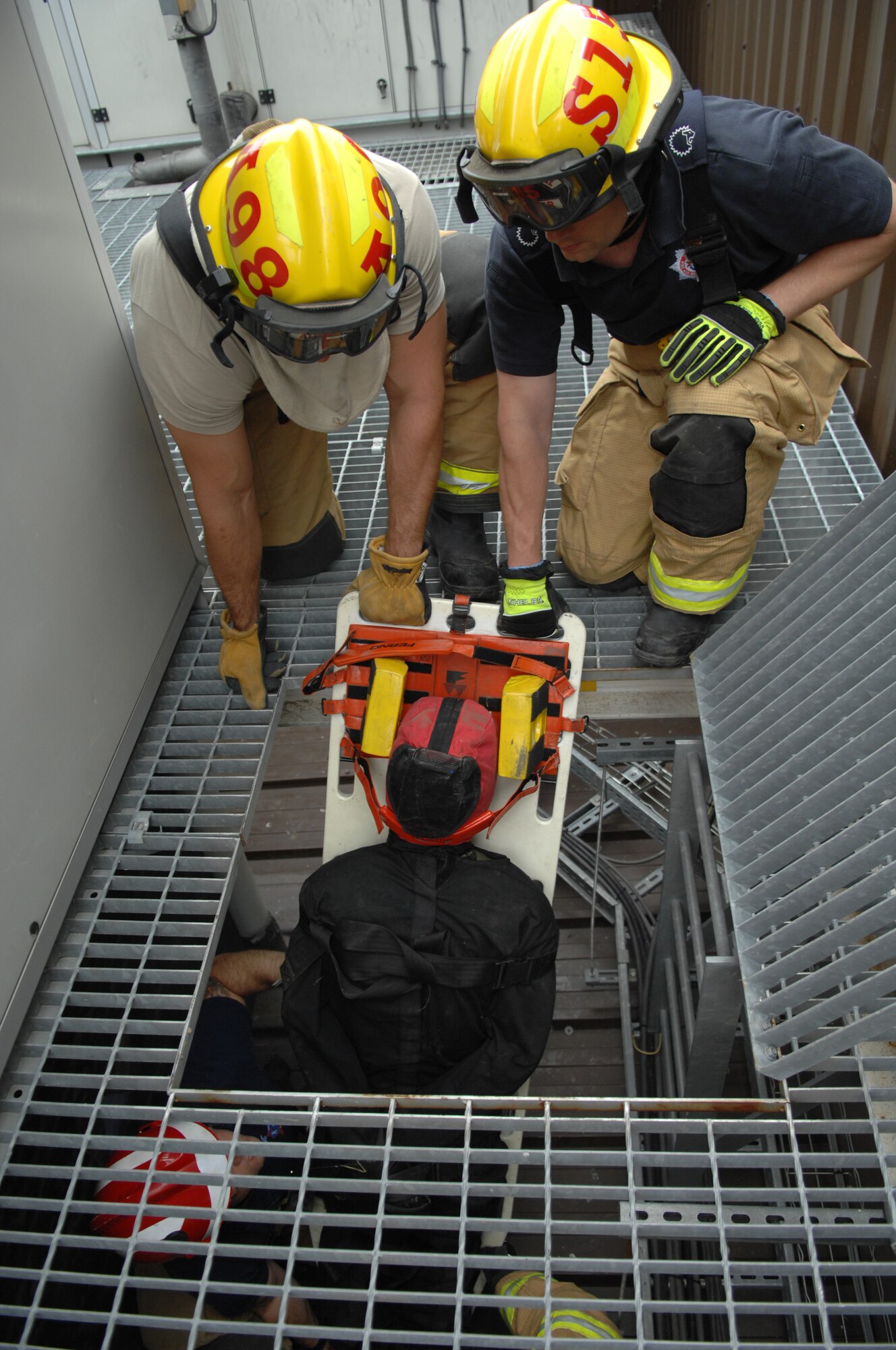 Firefighters from the 100th Civil Engineer Squadron Fire Department pull a simulated casualty from a confined space July 2, 2013, as part of a confined-space-rescue training exercise in building 809 on RAF Mildenhall, England. The “casualty” was secured to a board to keep from getting injured as he was pulled to safety. Firefighters then transferred the casualty to a more rounded securement in order to transport him through the building. (U.S. Air Force photo by Airman 1st Class Dillon Johnston/Released)
