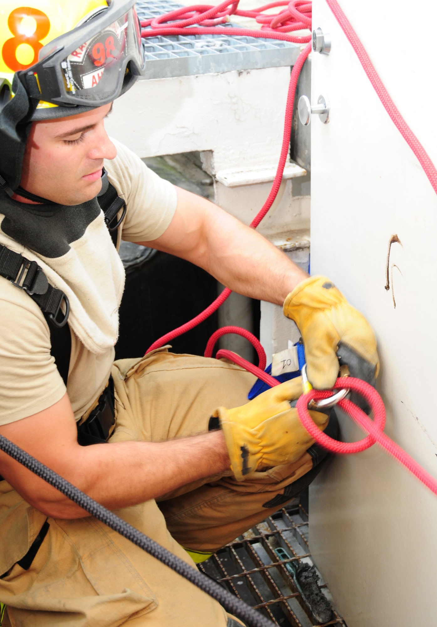 Senior Airman Brandon Ah You, 100th Civil Engineer Squadron Fire Department firefighter from Thousand Oaks, Calif., prepares to operate a belay line July 2, 2013, on RAF Mildenhall, England. The line, which was attached to a simulated casualty, acted as a reserve safety line when the victim was lowered down a ladder from the roof of building 809 during confined space rescue training. (U.S. Air Force photo by Karen Abeyasekere/Released)