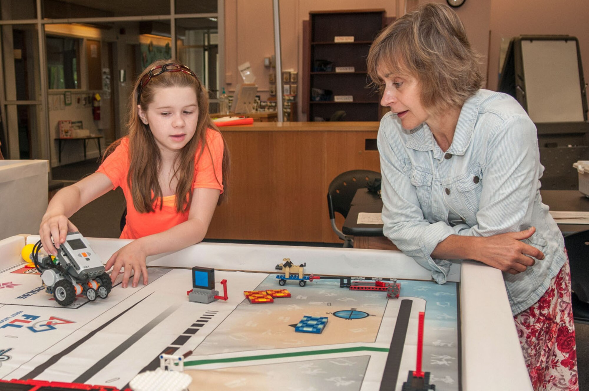 HANSCOM AIR FORCE BASE, Mass. – Maddy Guistwite (left) discusses the robotic challenge she is working on with Pat Cahill at a summer camp held at the STARBASE Academy on Hanscom July 10. STARBASE is a Department of Defense initiative that targets Title I schools and at-risk youth to get them excited about science, technology, engineering and math. (Photo by Rick Berry)