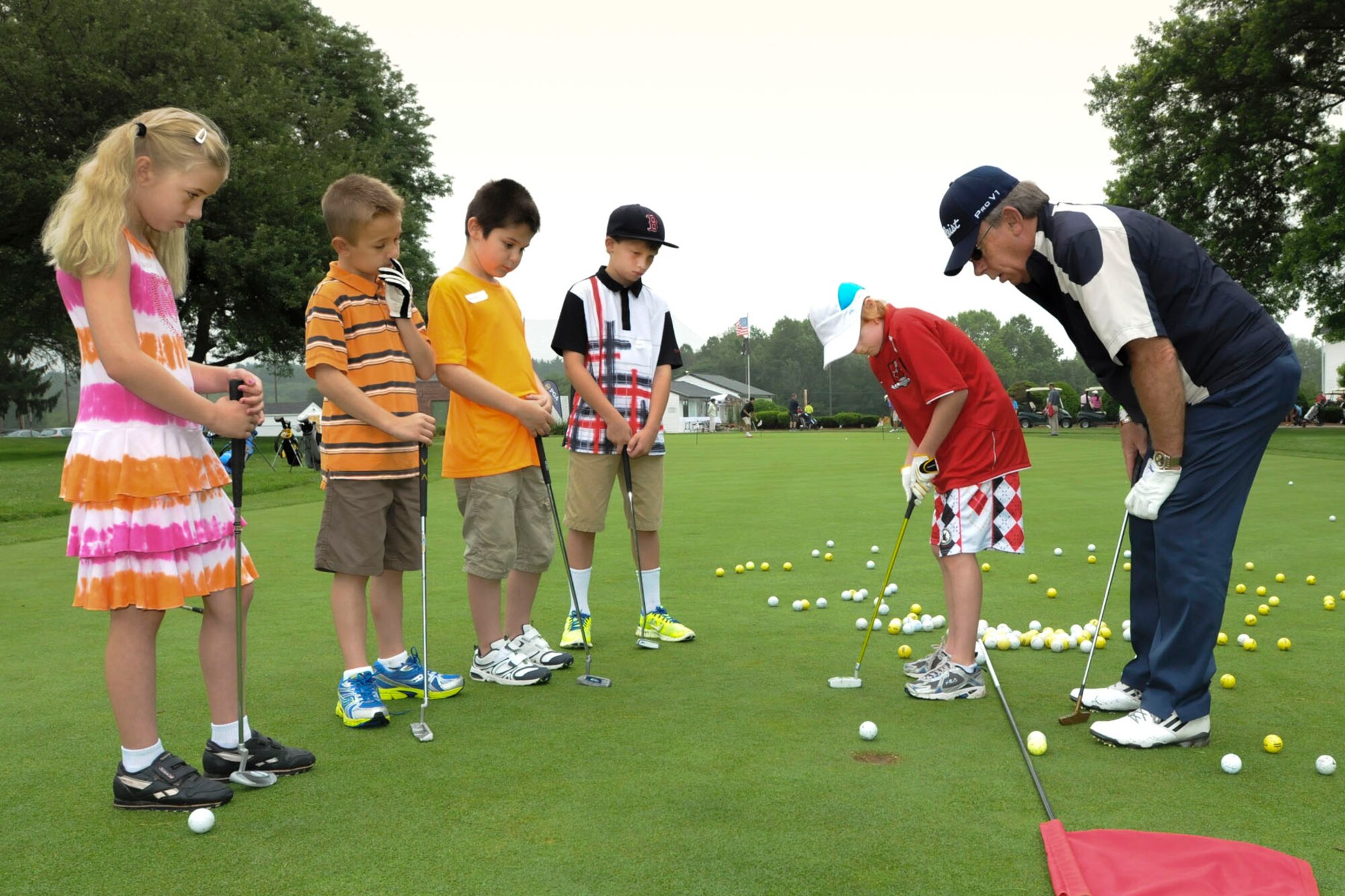 BEDFORD, Mass. -- Chip Hoar, a volunteer golf instructor, assists Matthew Guy on his putting game during the Golf 4 Kids Camp at the base golf course July 10 as (left to right) Alyssa Grunwald, Jackson Maddox, Hudson Gilmartin and Owen Hickey look on. Campers received a solid foundation in golf, which included swing mechanics, etiquette, terminology and how to maintain the speed of play. The next golf session will be held Aug. 13 through 16 at the Patriot Golf Course from 9 a.m. to noon. Contact the Pro Shop to sign up. (U.S. Air Force photo by Walter Santos)