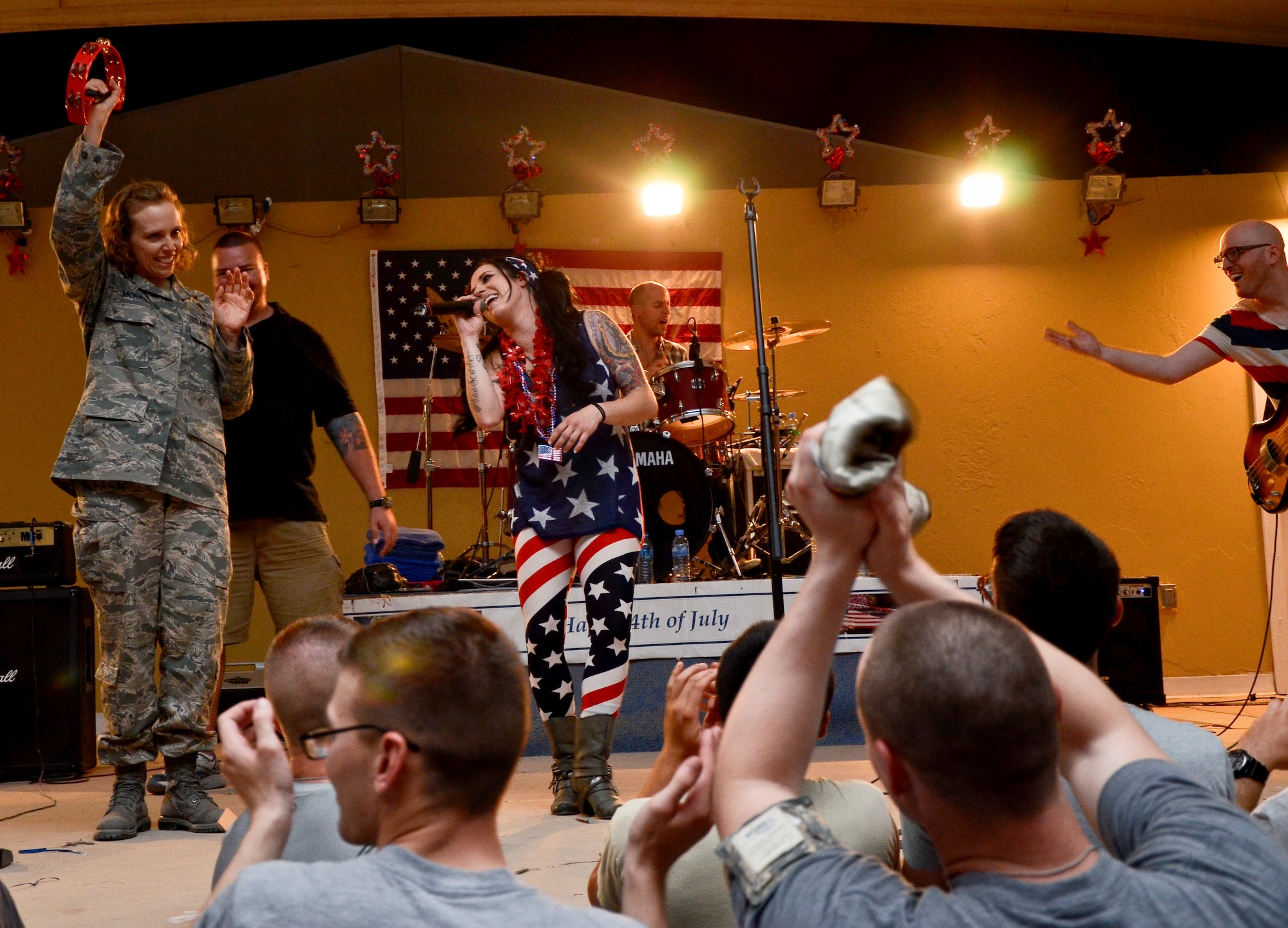 Lt. Col. Sirena Morris rocks out with events band, The Ringers, during the July Fourth celebration at the 379th Air Expeditionary Wing in Southwest Asia, July 4, 2013. The Ringers are a wedding and event band on tour from Minneapolis, Minn., and are back by popular request. After the first few songs, 379th AEW service members packed the stage, participated in a dance-off, and hung on every note until the band could play no more. Morris is the 379th Expeditionary Force Support Squadron commander. (U.S. Air Force photo/Senior Airman Benjamin Stratton)