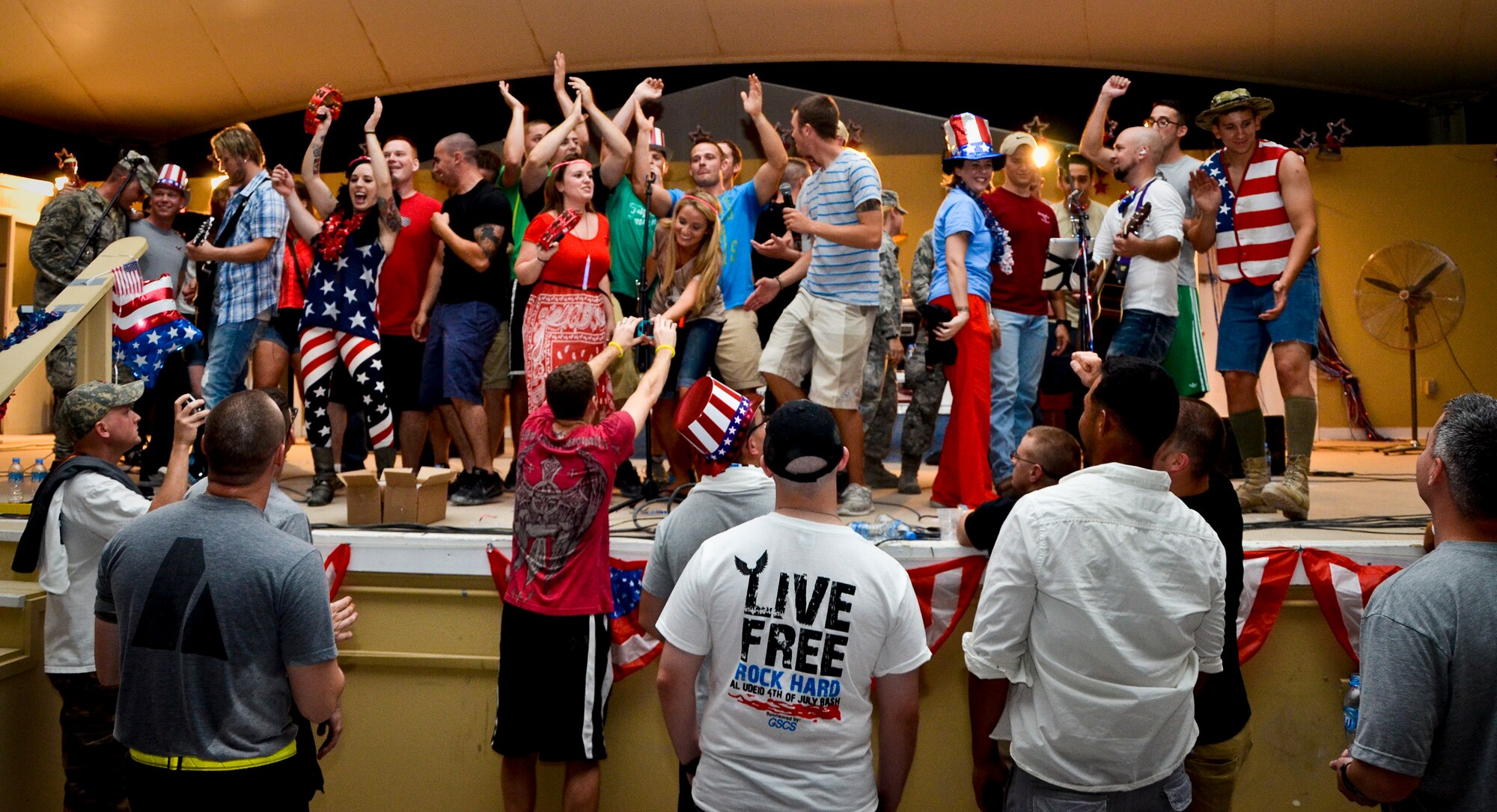 Grand Slam Wing service members rock out with events band, The Ringers, during the July Fourth celebration at the 379th Air Expeditionary Wing in Southwest Asia, July 4, 2013. The Ringers are a wedding and event band on tour from Minneapolis, Minn., and are back by popular request. After the first few songs, 379th AEW service members packed the stage, participated in a dance-off, and hung on every note until the band could play no more. (U.S. Air Force photo/Senior Airman Benjamin Stratton)