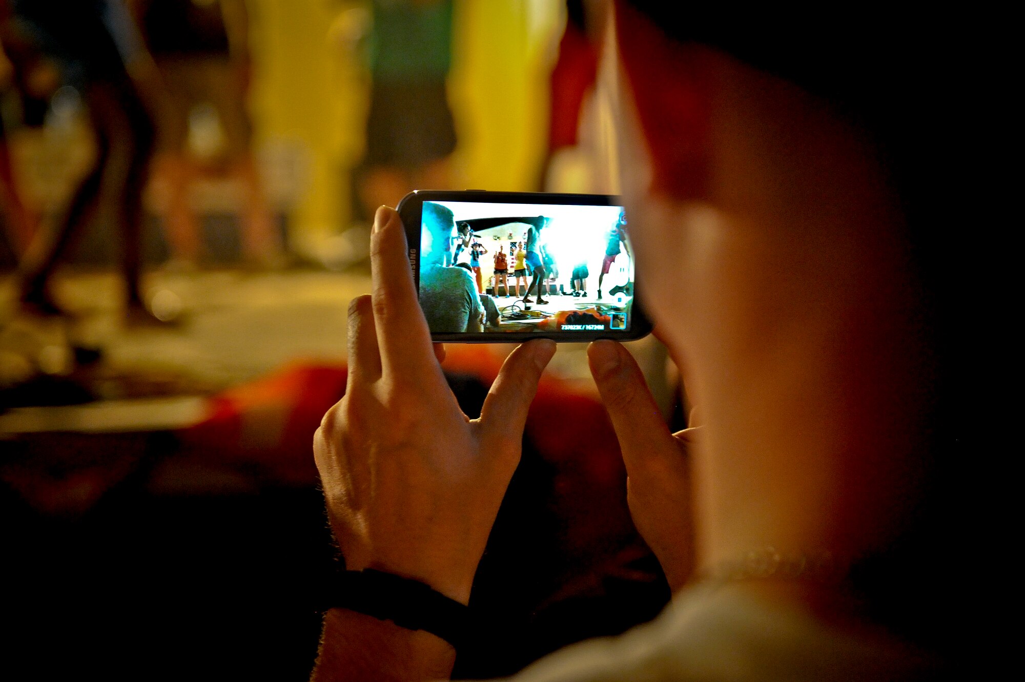 A 379th Air Expeditionary Wing service member captures a dance-off competition on his smartphone as part of The Ringers musical performance during the July Fourth celebration at the 379th AEW in Southwest Asia, July 4, 2013. The Ringers are a wedding and event band on tour from Minneapolis, Minn., and are back by popular request. The dance-off was judged by crowd noise and winners won a free t-shirt and bragging rights. (U.S. Air Force photo/Senior Airman Benjamin Stratton)