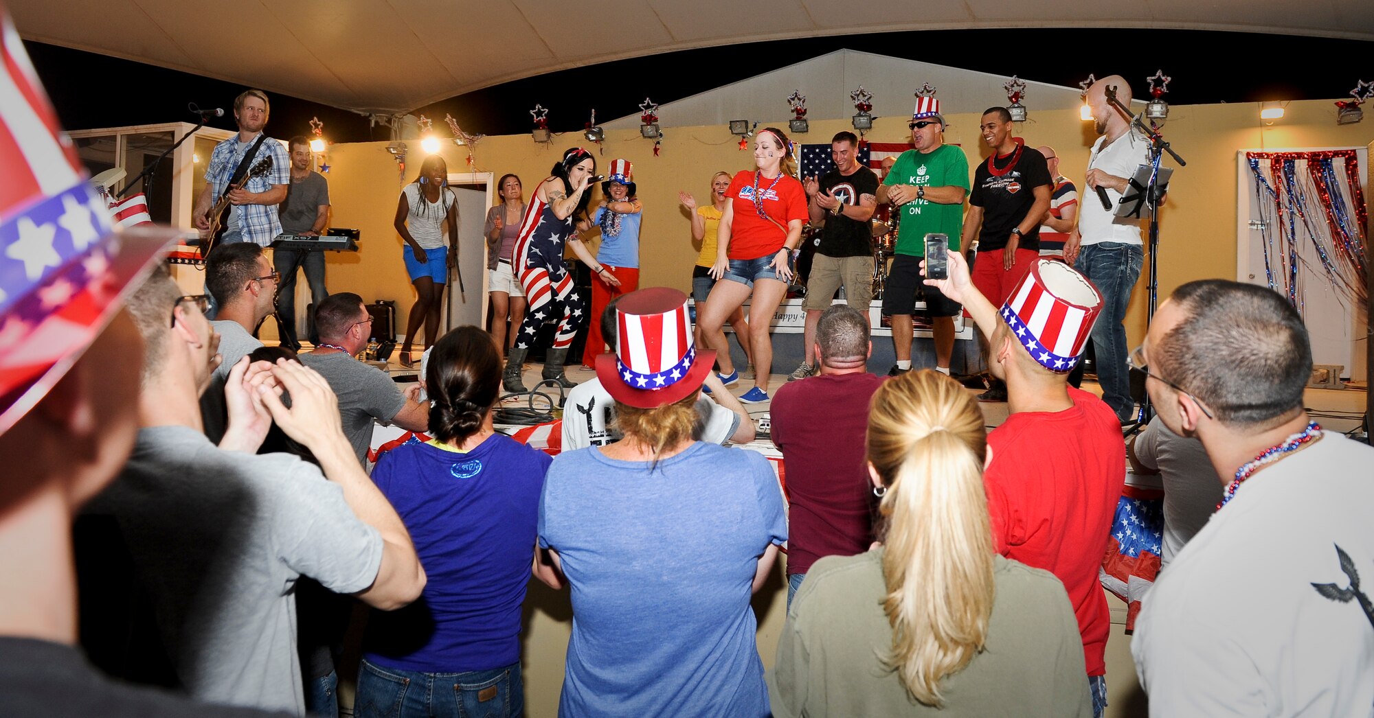 Events band, The Ringers, brought service members on stage for a dance-off competition judged by crowd noise during the July Fourth celebration at the 379th Air Expeditionary Wing in Southwest Asia, July 4, 2013. The Ringers are a wedding and event band on tour from Minneapolis, Minn., and are back by popular request. After the first few songs, 379th AEW service members packed the stage, participated in a dance-off, and hung on every note until the band could play no more. (U.S. Air Force photo/Senior Airman Benjamin Stratton)