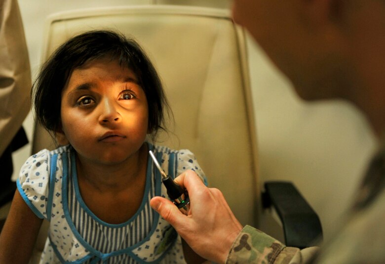 Maj. Marcus Neuffer, 455th Expeditionary Medical Group ophthalmologist, examines and compares the eyes of a six-year-old Afghan patient in the Joint Craig Theater Hospital Ophthalmologist Clinic on Bagram Airfield, Afghanistan, July 6, 2013. He recently completed a surgery on her right eye to correct a cataract. The girl had been diagnosed with cataracts in both eyes in May. A cataract is an eye disease in which the clear lens of the eye becomes cloudy and opaque, causing a decrease in vision. The lens is replaced in surgery, without treatment a cataract can result in a complete loss of vision. (U.S. Air Force photo/ Staff Sgt. Stephenie Wade)


