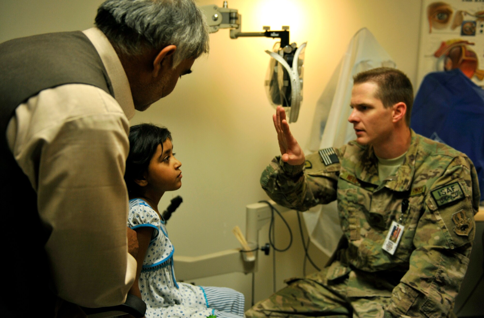 Maj. Marcus Neuffer, 455th Expeditionary Medical Group ophthalmologist, uses his hands to check the depth of field of a six-year-old Afghan patient in the Craig Joint Theater Hospital Ophthalmologist Clinic on Bagram Airfield, Afghanistan, July 6, 2013. He recently completed a surgery on her right eye to correct a cataract. Prior to the procedure she was unable to see and her father had to carry her. When she came in for the follow-up appointment July 6, she was able to walk by herself and could read the letters on the chart. Neuffer is deployed from Keesler Air Force Base, Miss. (U.S. Air Force photo/ Staff Sgt. Stephenie Wade)